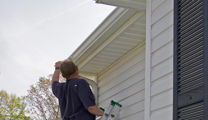 Person installing gutters on the house