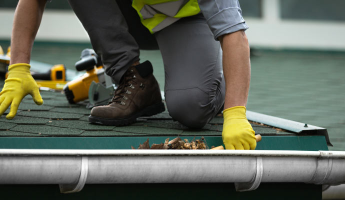 A professional cleaning a gutter