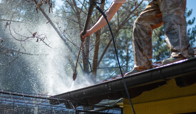 A professional pressure washing a gutter