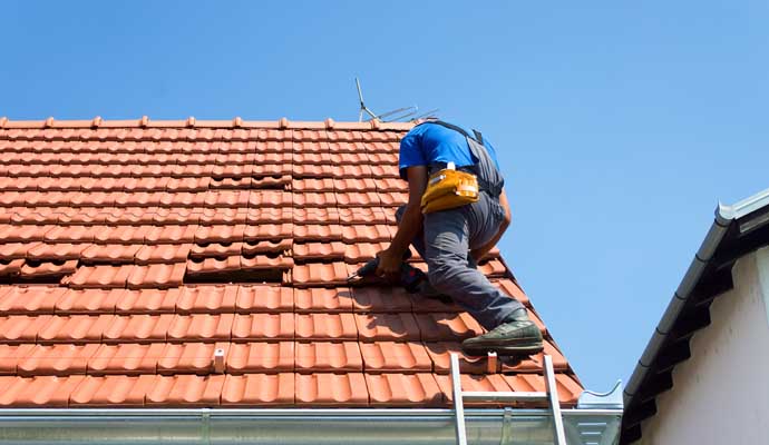 Professional repairing a tile roof using an equipment