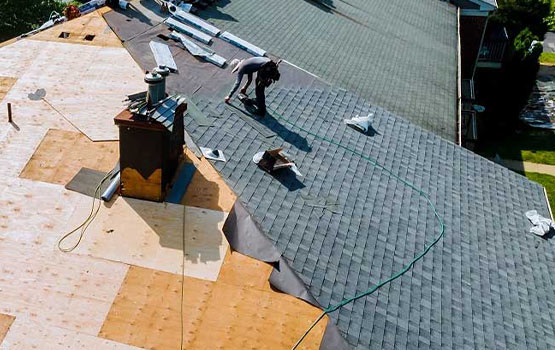 workers laying down shingles and securing them in place.