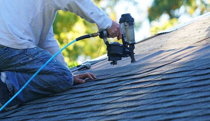 Professional repairing shingles roof using equipment