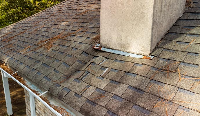 A roof with asphalt shingles showing visible damage and wear