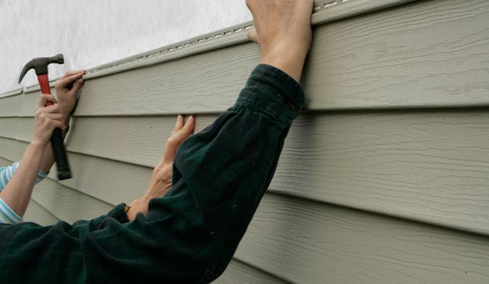 Person installing siding with equipment